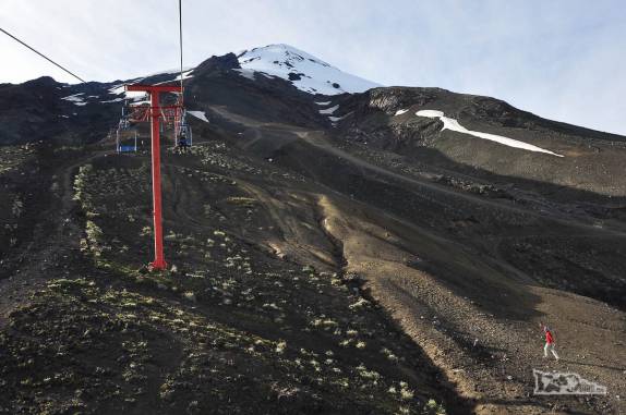 A Ana, de teleférico, passa pelo Rodrigo, a pé, no início da subida do vulcão Villarrica, região de Pucón, no sul do Chile